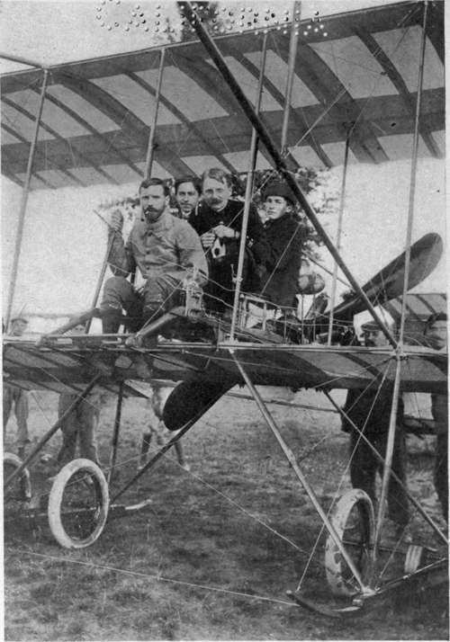 Henry Farman seated in his biplane with three passengers.